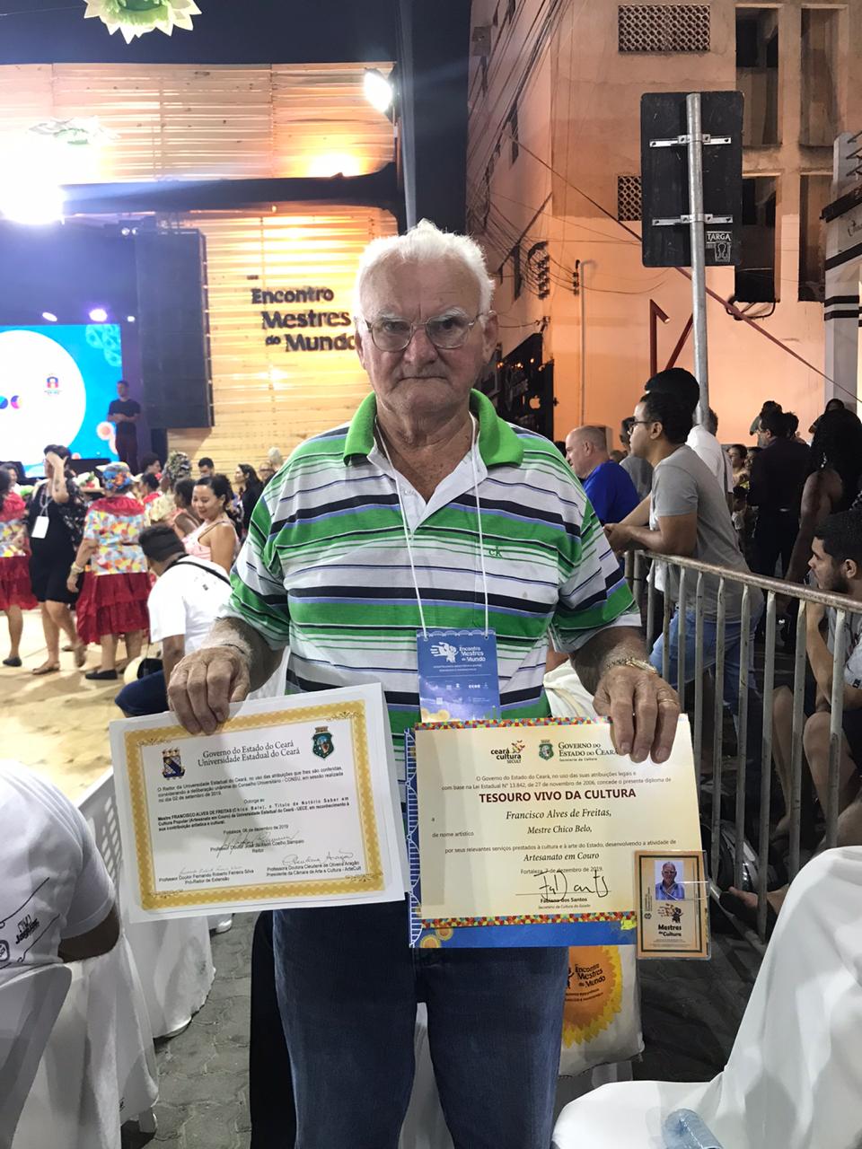 Mestre Chico Belo segurando com orgulho seus diplomas de Notório Saber e Tesouro Vivo da Cultura